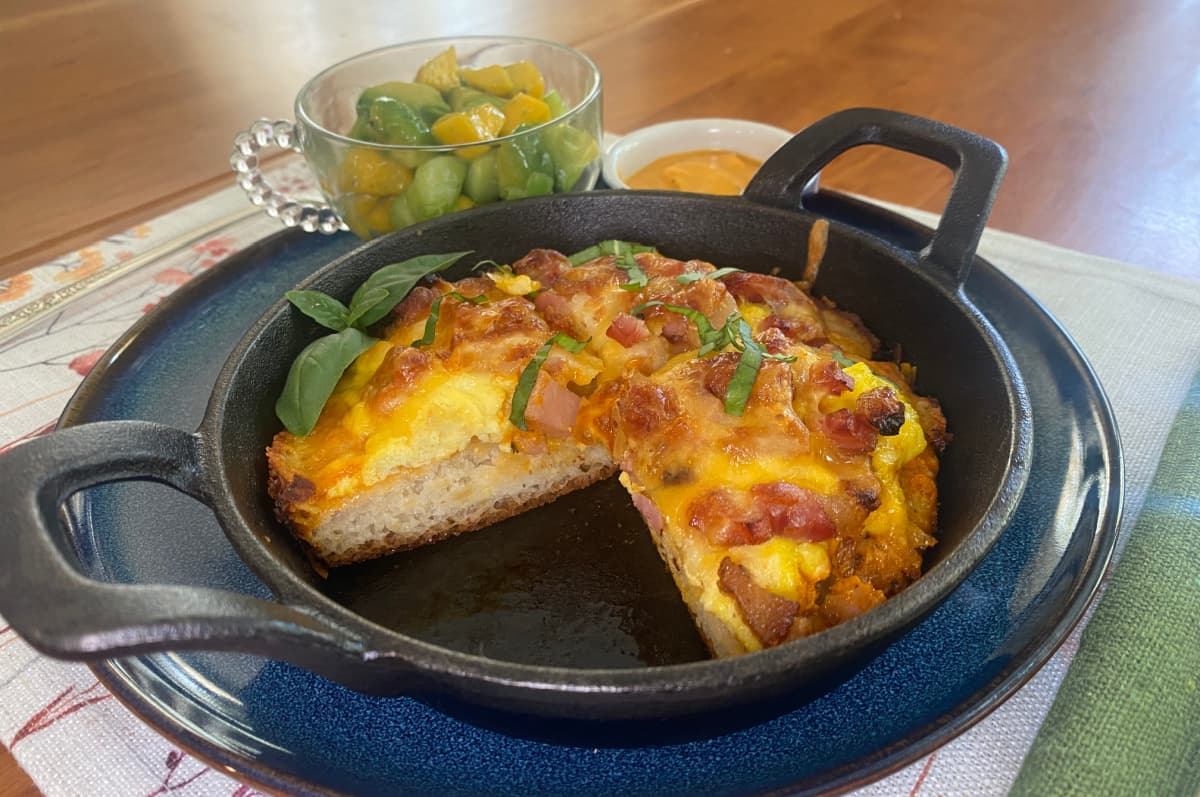 Baked cast iron breakfast pizza with a slice cut out. 