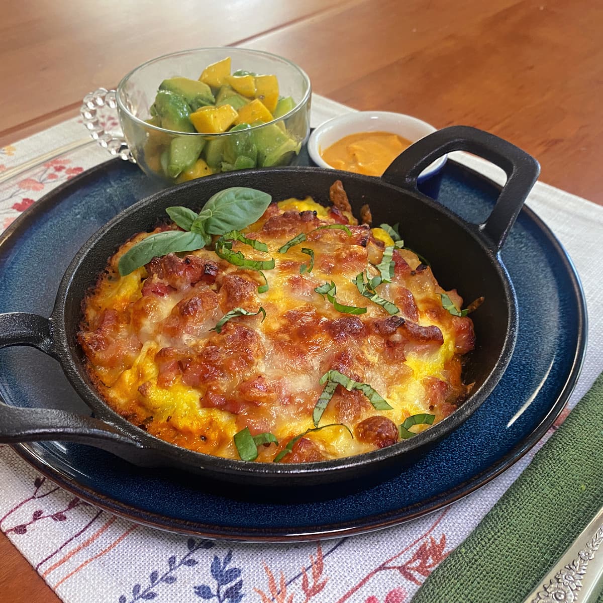 Mini cast iron breakfast pizzas topped with scrambled eggs, melted cheese, bacon, and vegetables, baked until golden and served in individual cast iron skillets.