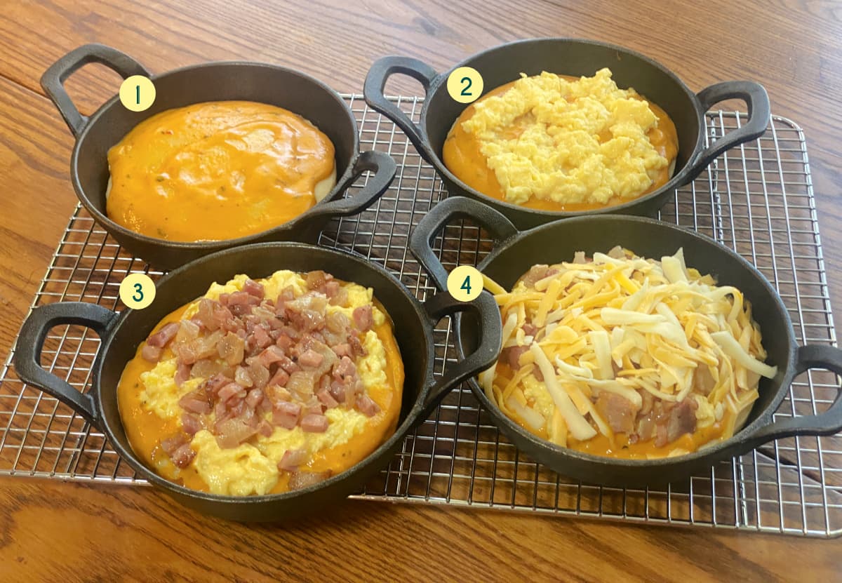 Breakfast pizzas topped with scrambled eggs, meat and veggies, and cheese before baking.