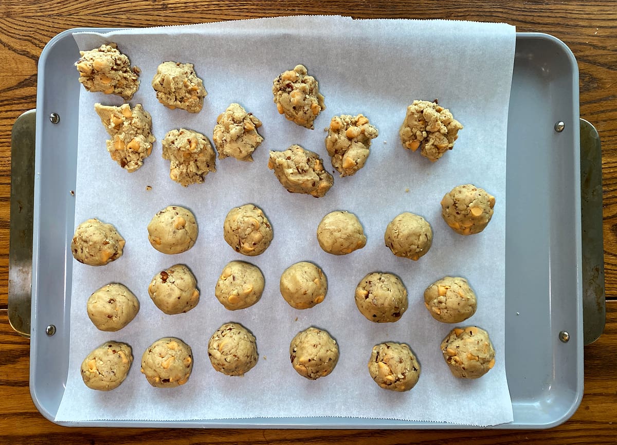 Scooped butterscotch pecan cookie dough balls on a parchment-lined baking sheet