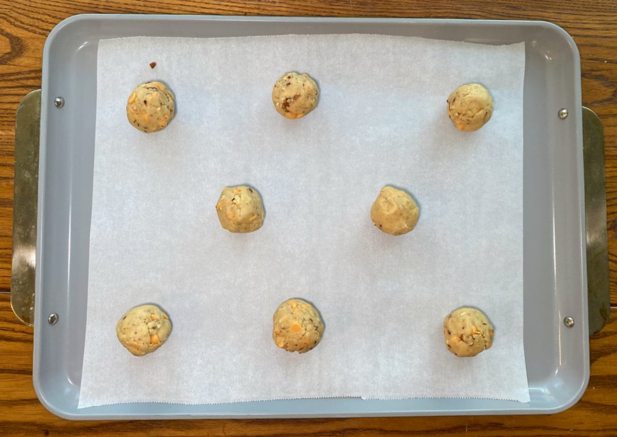 Hand-rolled butterscotch pecan cookie dough balls on a parchment-lined baking sheet