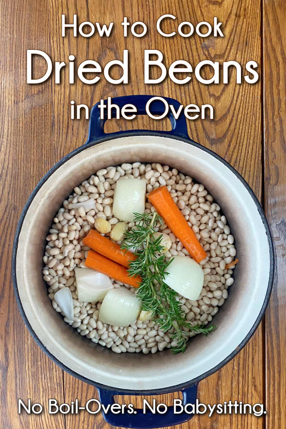 Dry navy beans and aromatics (rosemary, onions, carrots, and garlic) in a cast iron Dutch oven. Pin text overly reads: How to Cook Dried Beans in the Oven | No Boilovers. No babysitting.
