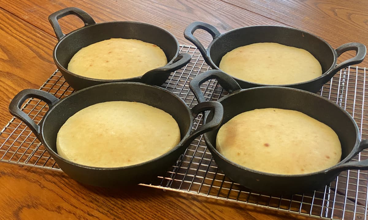 Mini cast iron skillet pizza crusts partially baked until lightly golden.