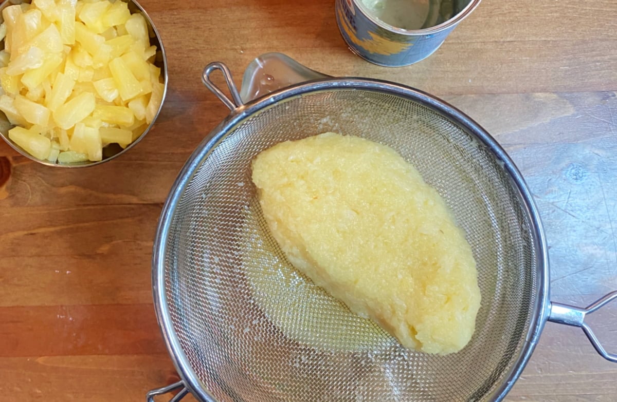Crushed pineapple draining in a sieve.