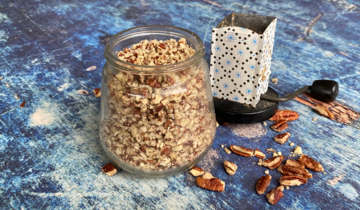 Old-fashioned nut-grinder filled with chopped pecans.